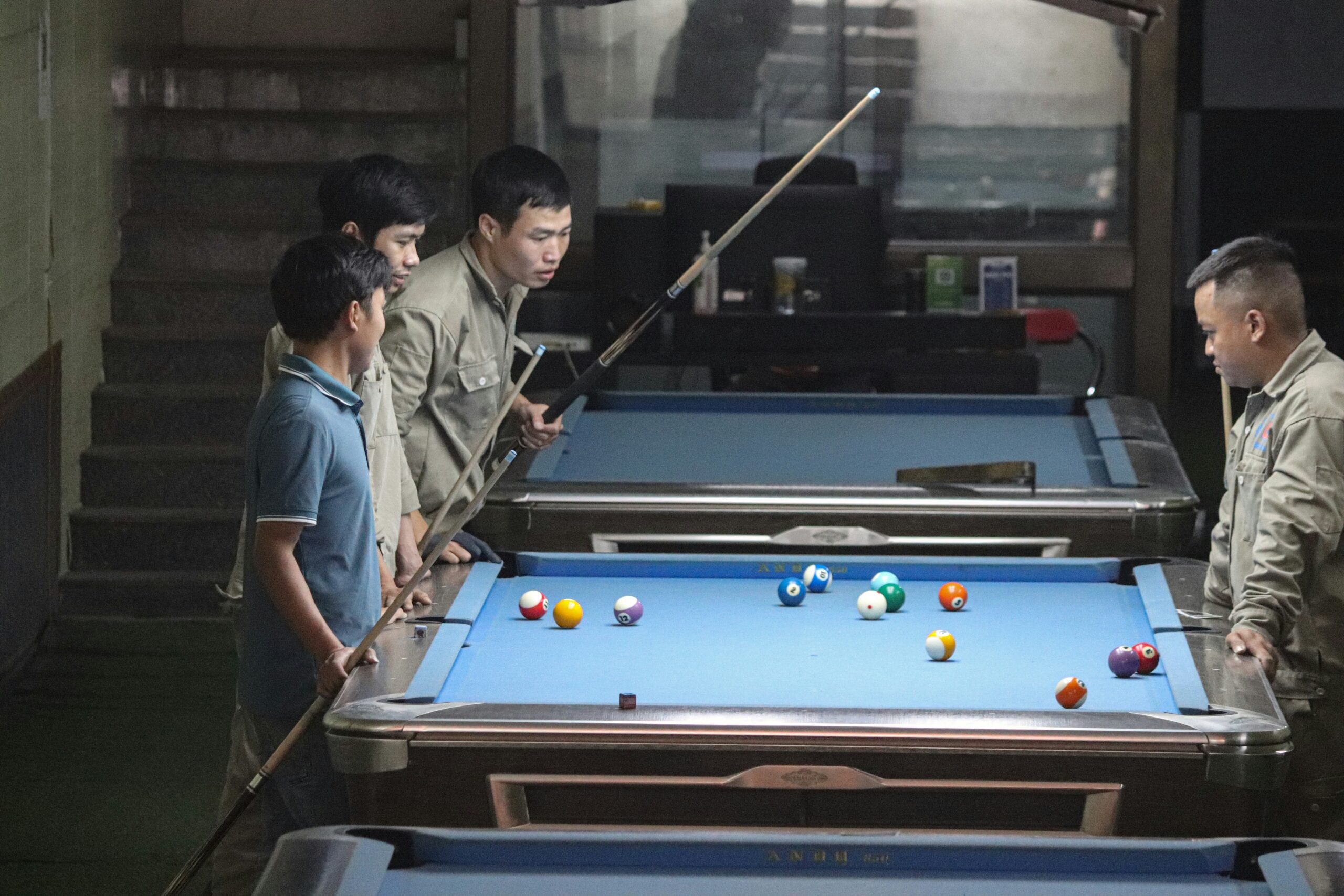 a group of men standing around a pool table