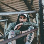 man sitting on stairway wearing green hooded jacket